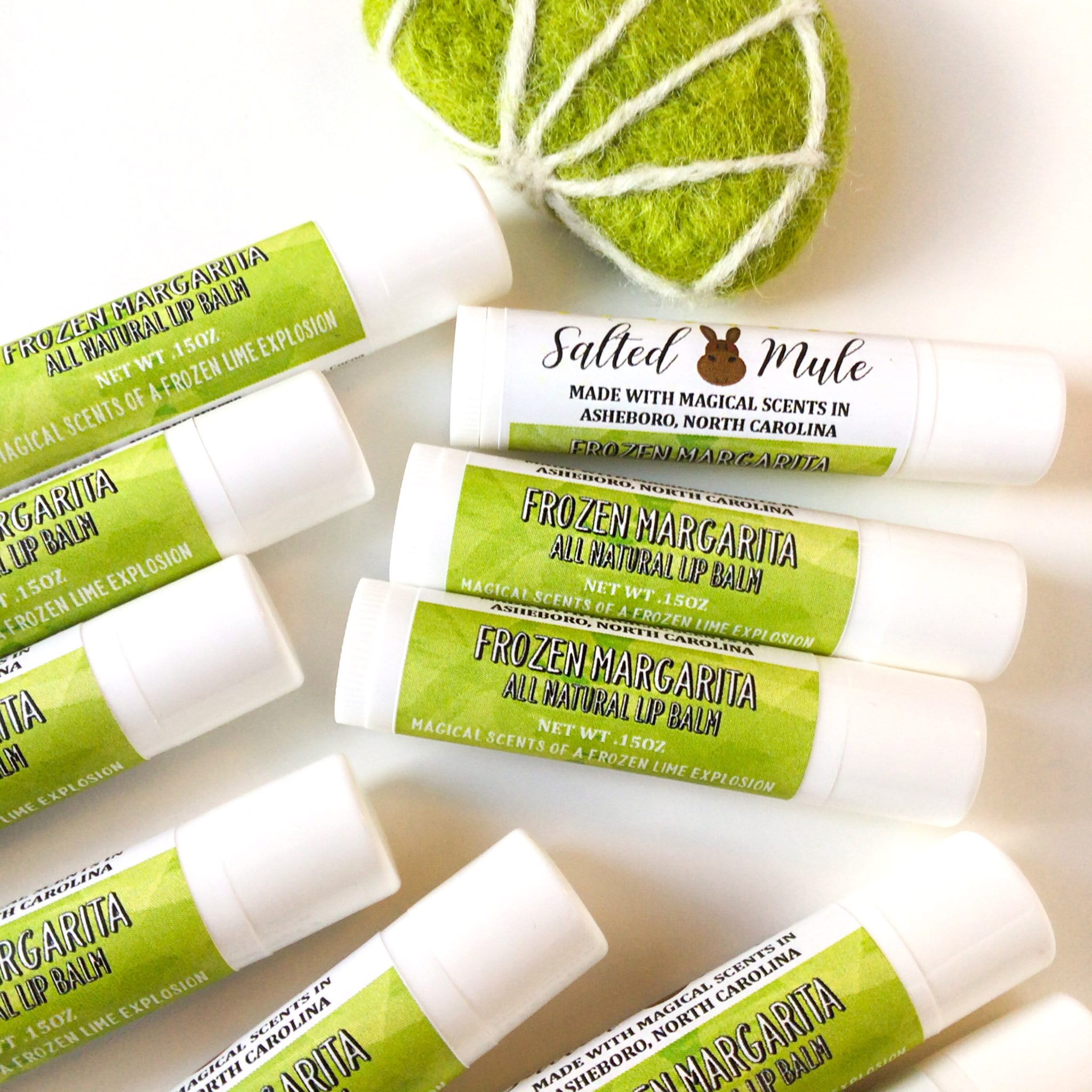 Lip balm tubes with white, green, and black labels, "Salted Mule" text visible, and lime decoration