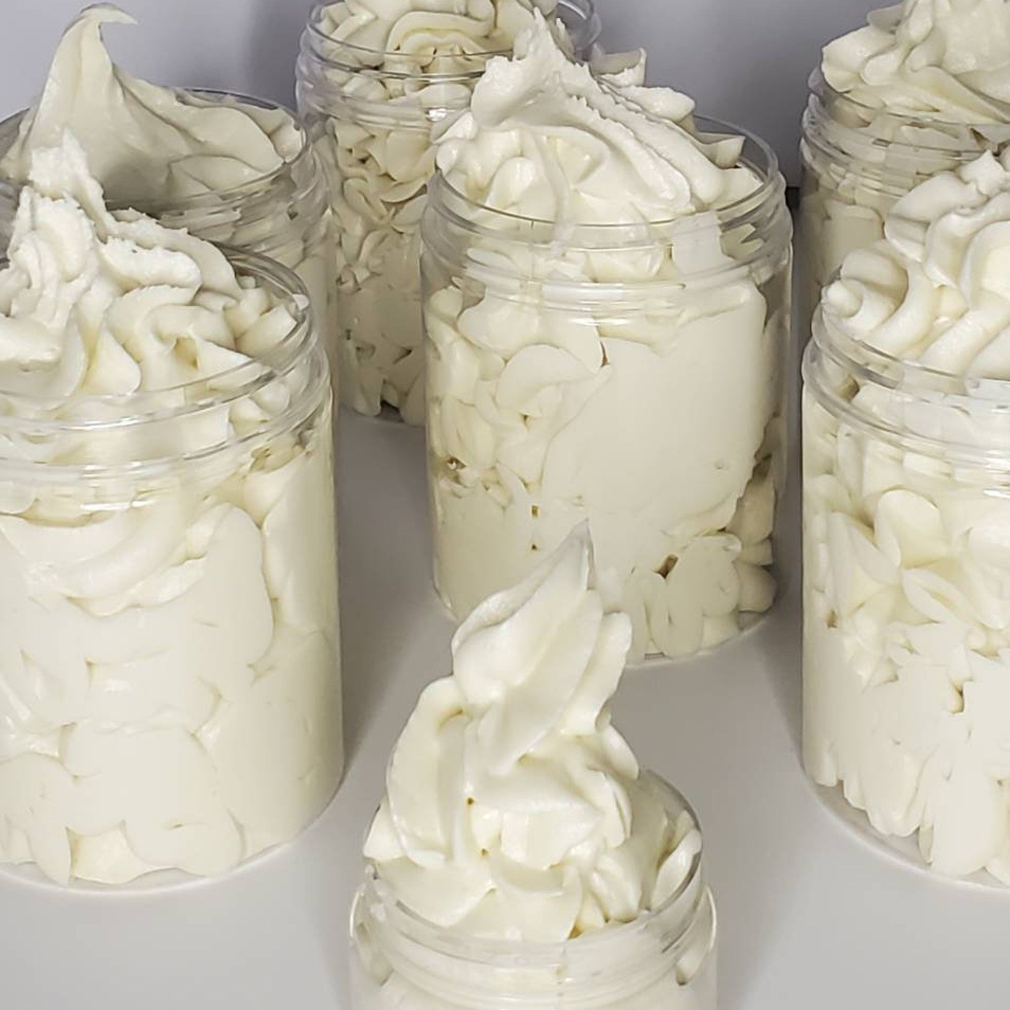 Body butter in clear jars, off-white whipped texture, cosmetic product display