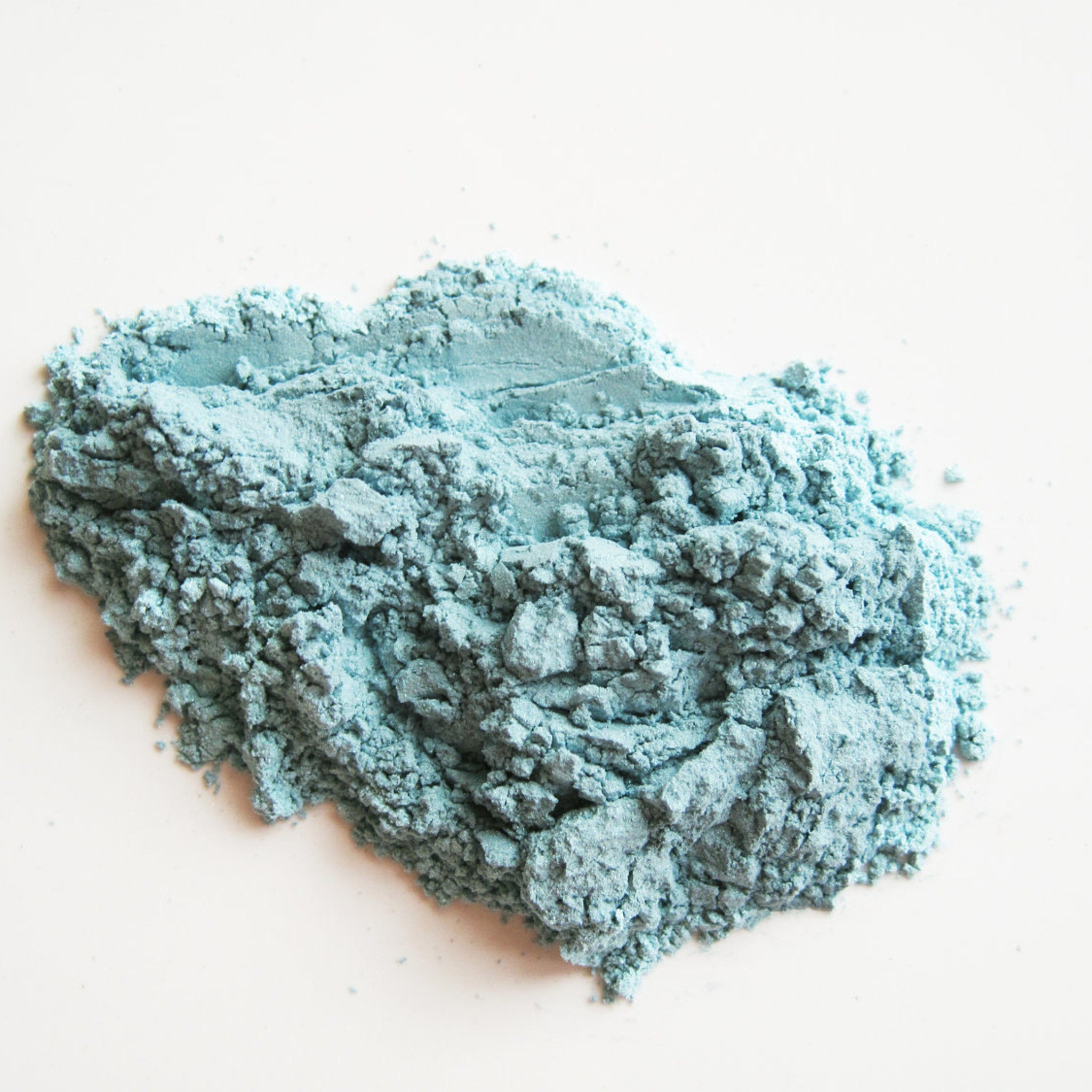 Close-up of matte Capri blue mineral eye shadow with smooth pressed powder texture in compact case
