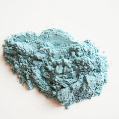 Close-up of matte Capri blue mineral eye shadow with smooth pressed powder texture in compact case