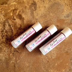 Lip balm tubes with white caps, pink label, and Bubble Love Boutique logo on brown surface