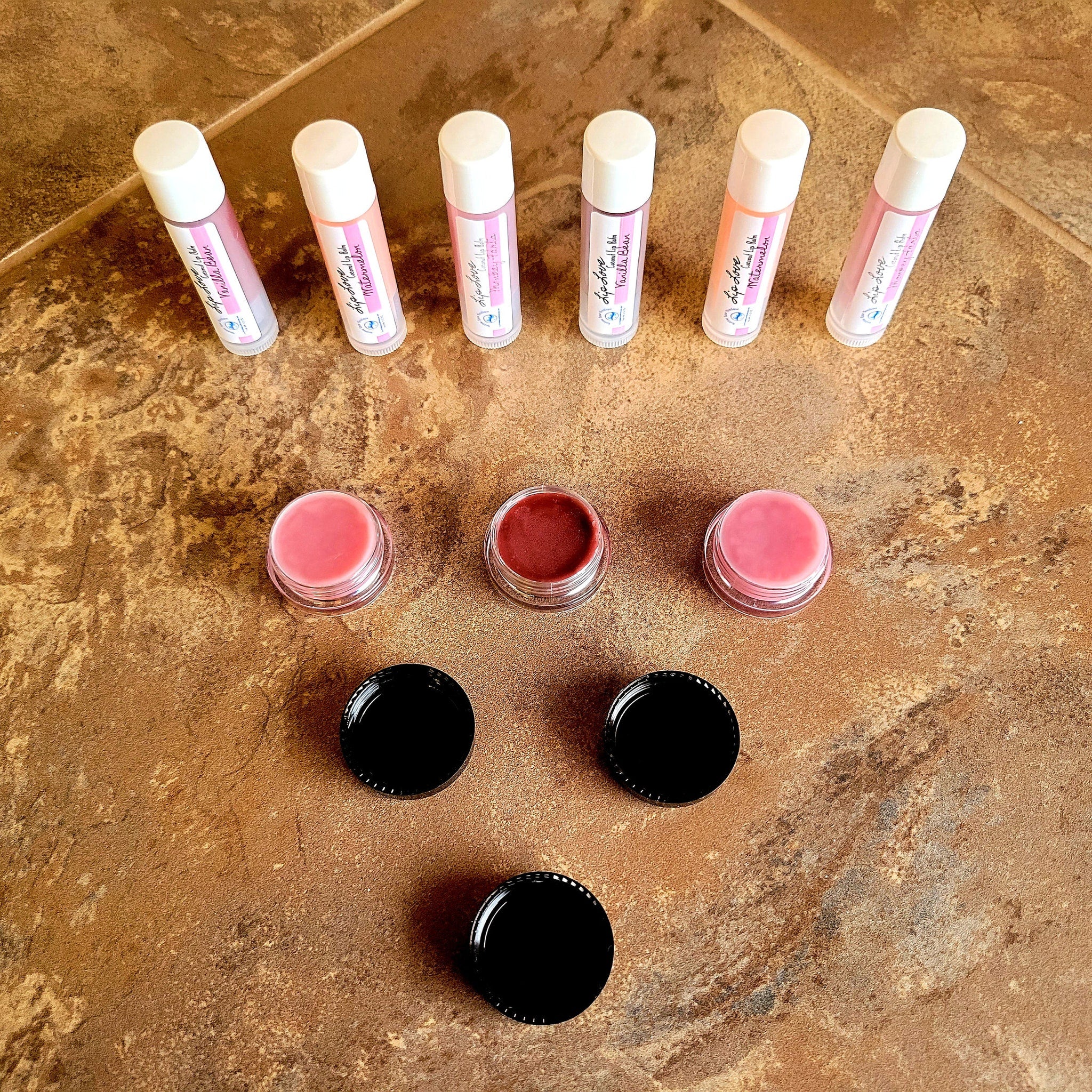 Lip balm tubes with white caps, pink labels, and Lip Love branding on a brown surface