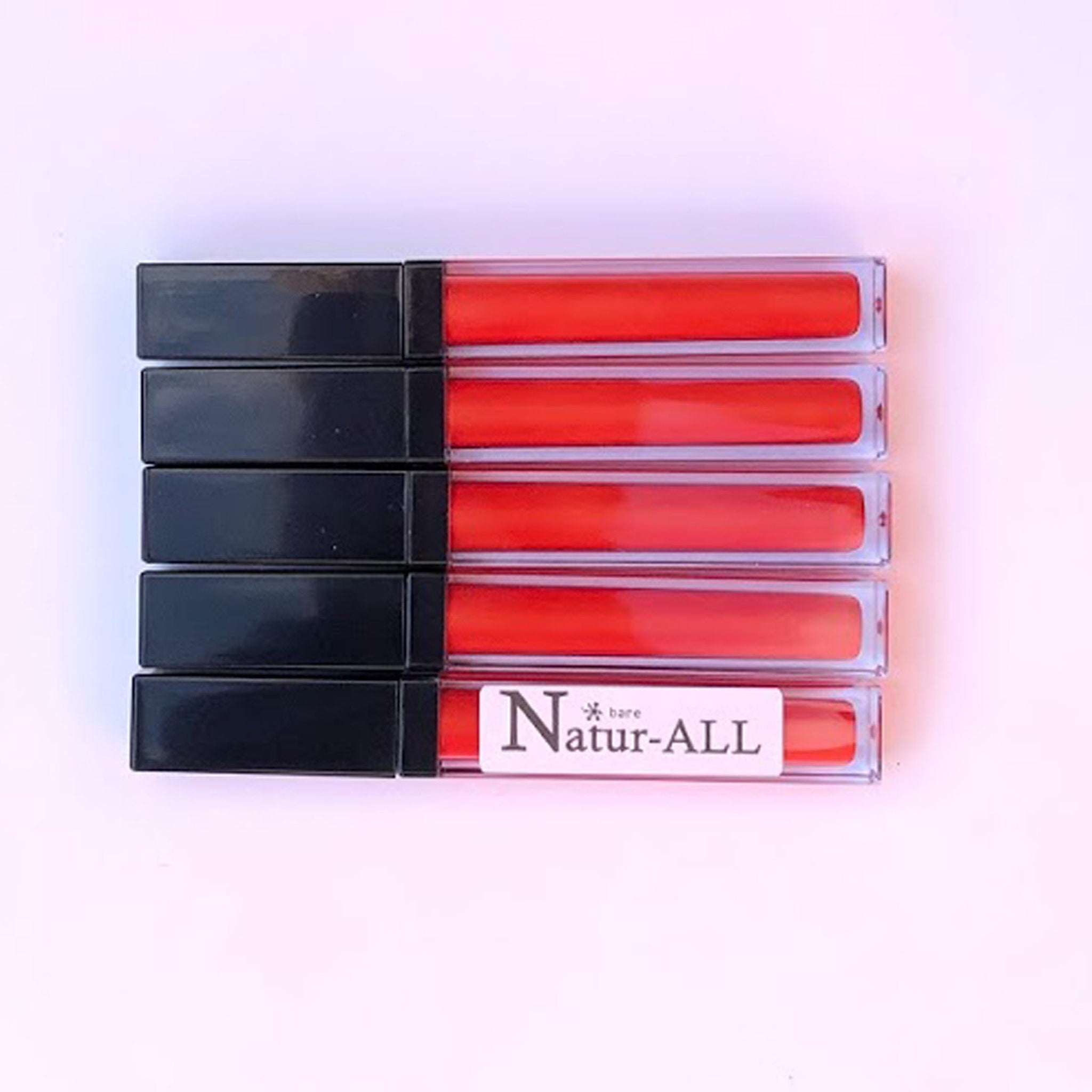 Lip gloss tubes with red gloss, black caps, and Natur-ALL branding