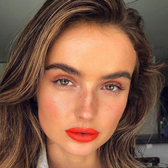 Makeup look featuring red lipstick, brown hair with highlights, and pink blush on a woman's face