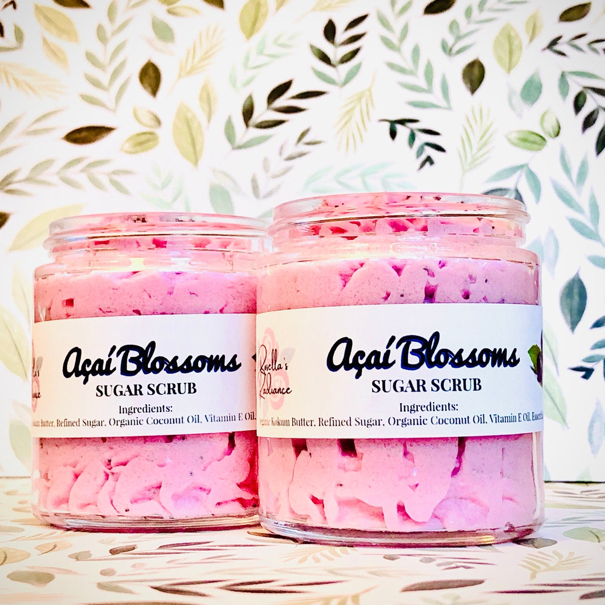 Elegant glass jar of whipped sugar scrub with pale pink lid and minimalist label, resting on marble surface