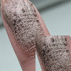 Hand applying bronze-beige duochrome eyeshadow with fingertip, showing metallic chromatic shift on eyelid