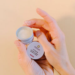 Lip balm in silver tin, white balm, and hands holding product with Annacare label visible