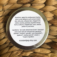 Healing salve in a silver tin with white label, on woven background, scoutandpep etsy text visible