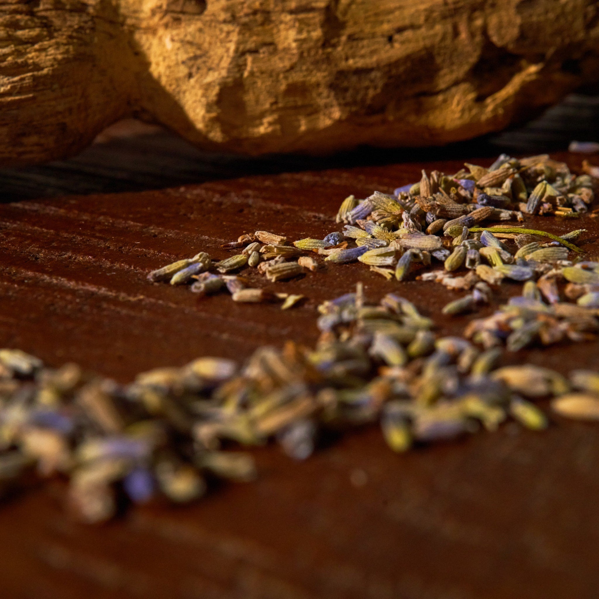 Dried lavender buds with purple and green hues on a brown wooden surface with a wooden background