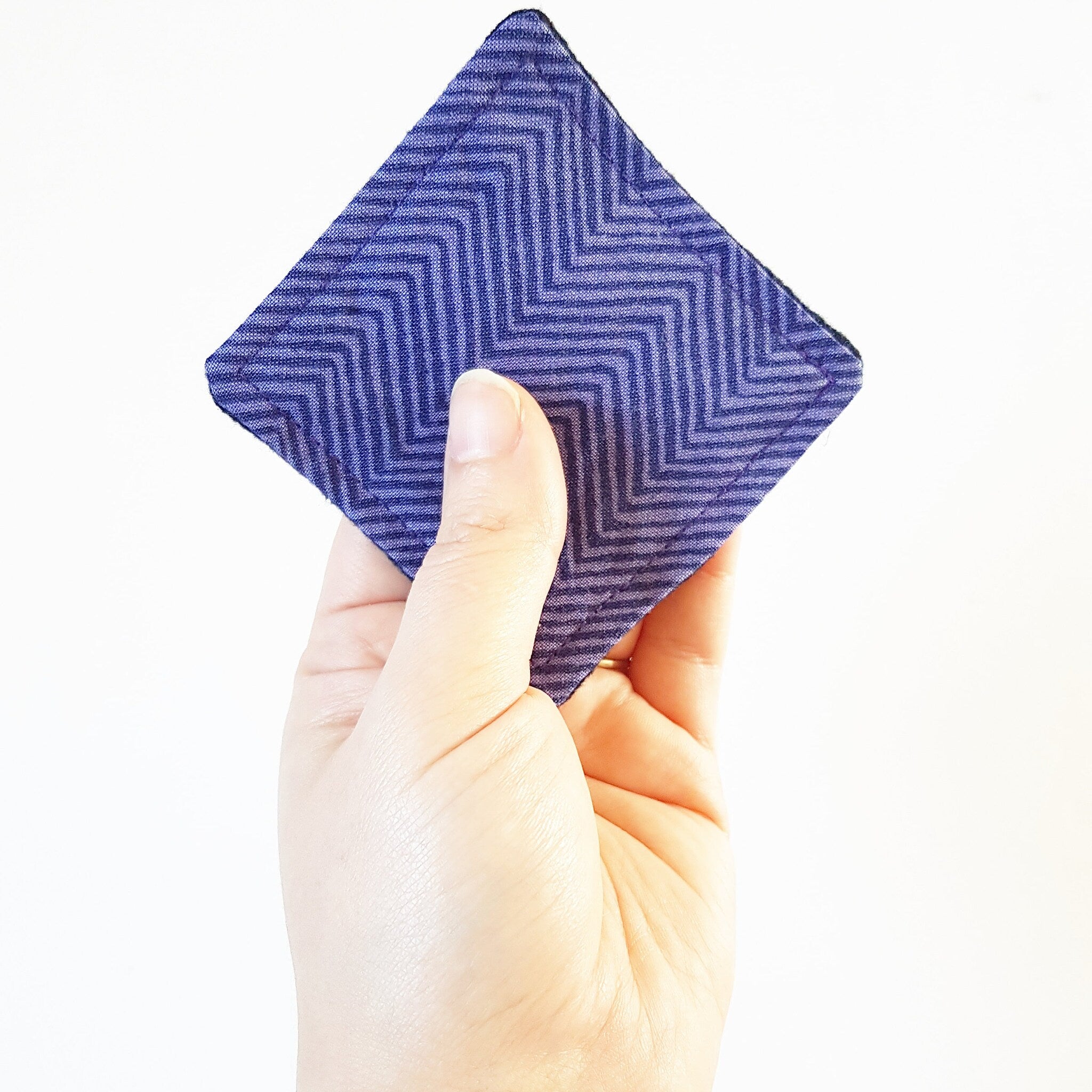 Coaster, blue fabric with chevron pattern, held in hand