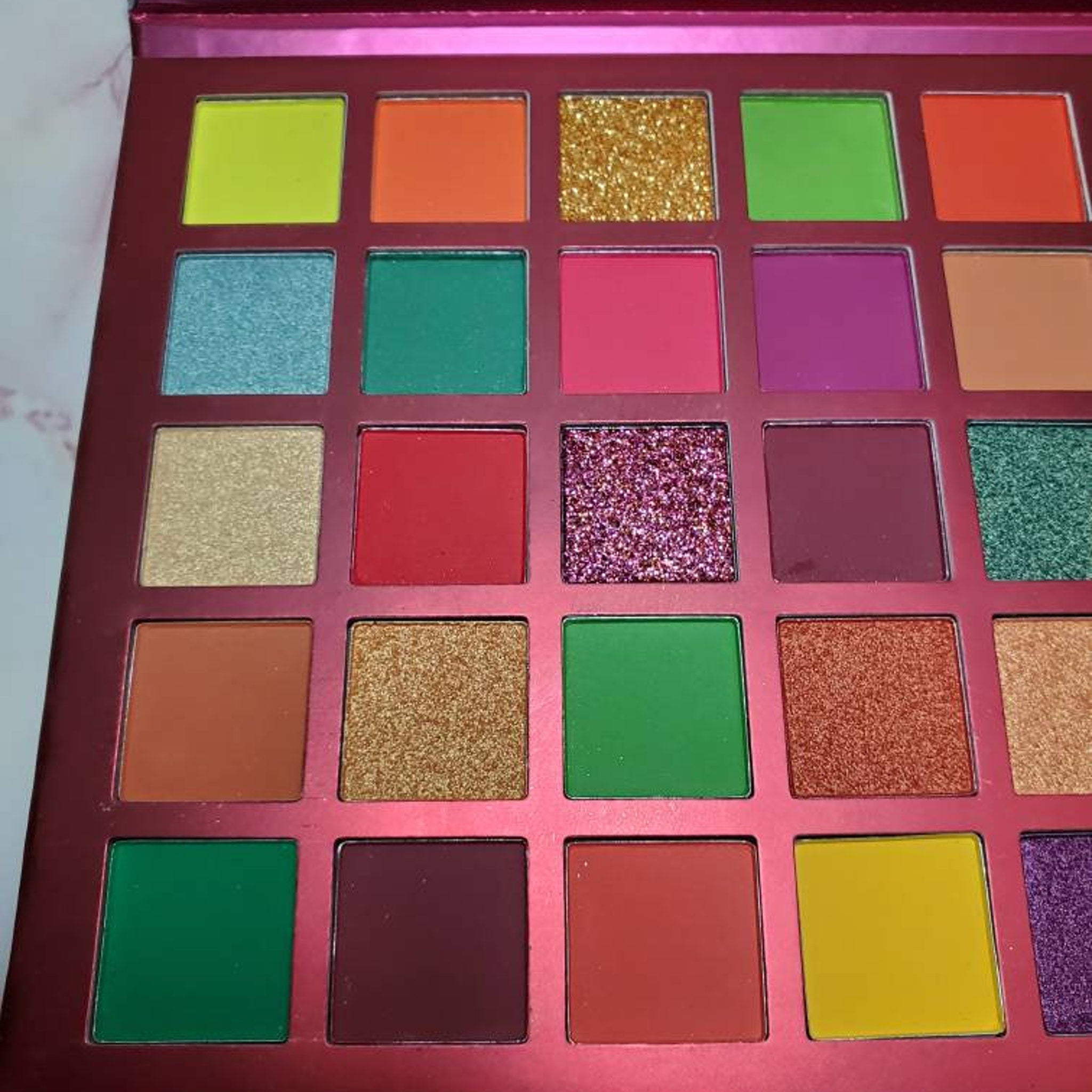 Side view of MI CORAZON eyeshadow palette showing matte and shimmer shades in warm tones with sleek black packaging