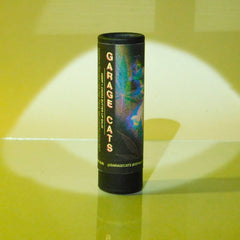 Lip balm tube, black paper, colorful abstract design, Garage Cats branding visible