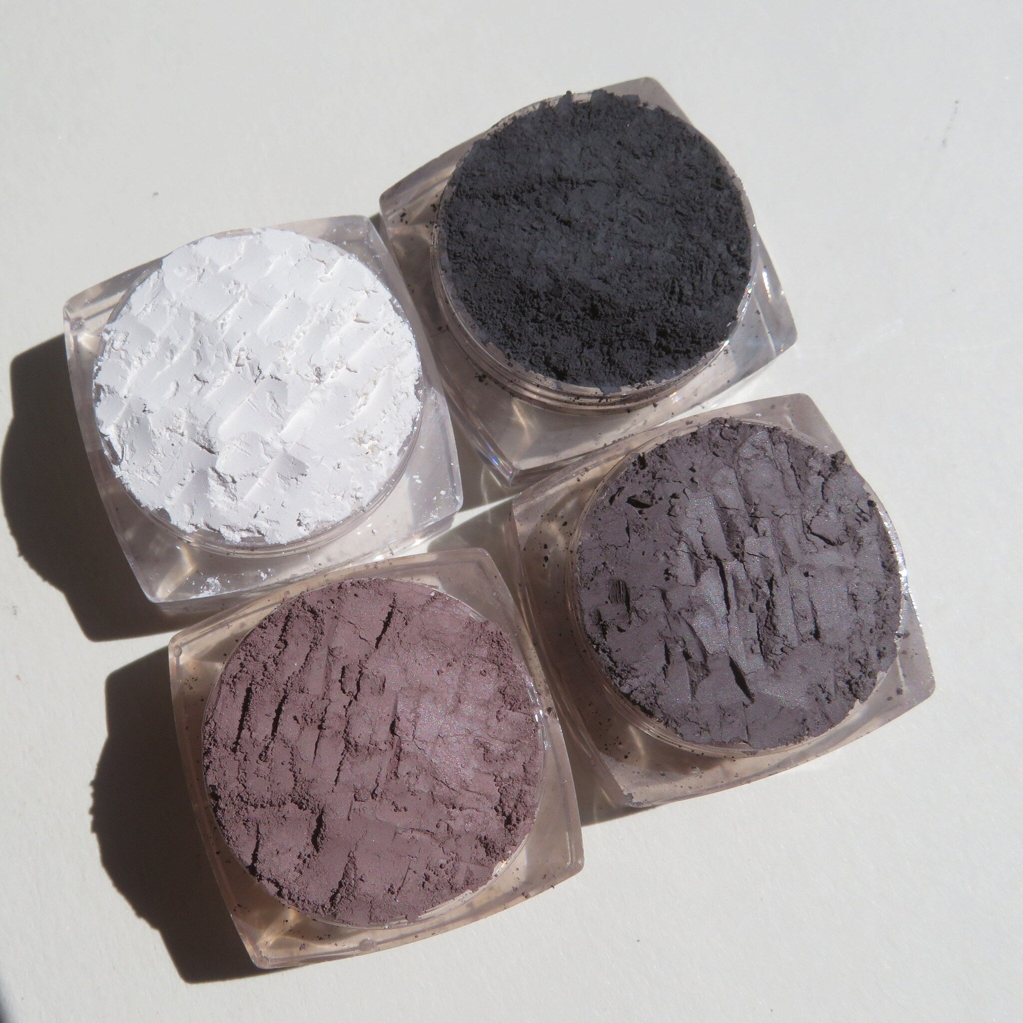 Hand applying shimmery loose mineral eyeshadow with a brush onto eyelid, showcasing smooth blendability