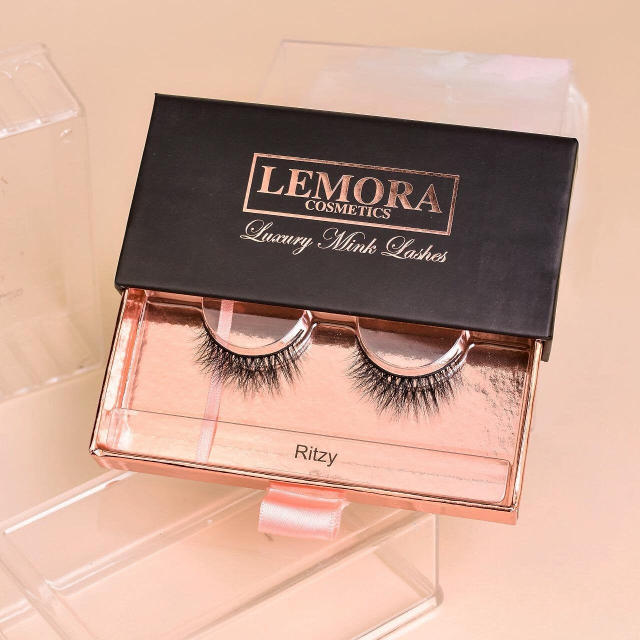 Eyelashes in black with pink and black box, Lemora Cosmetics brand name visible, Ritzy style