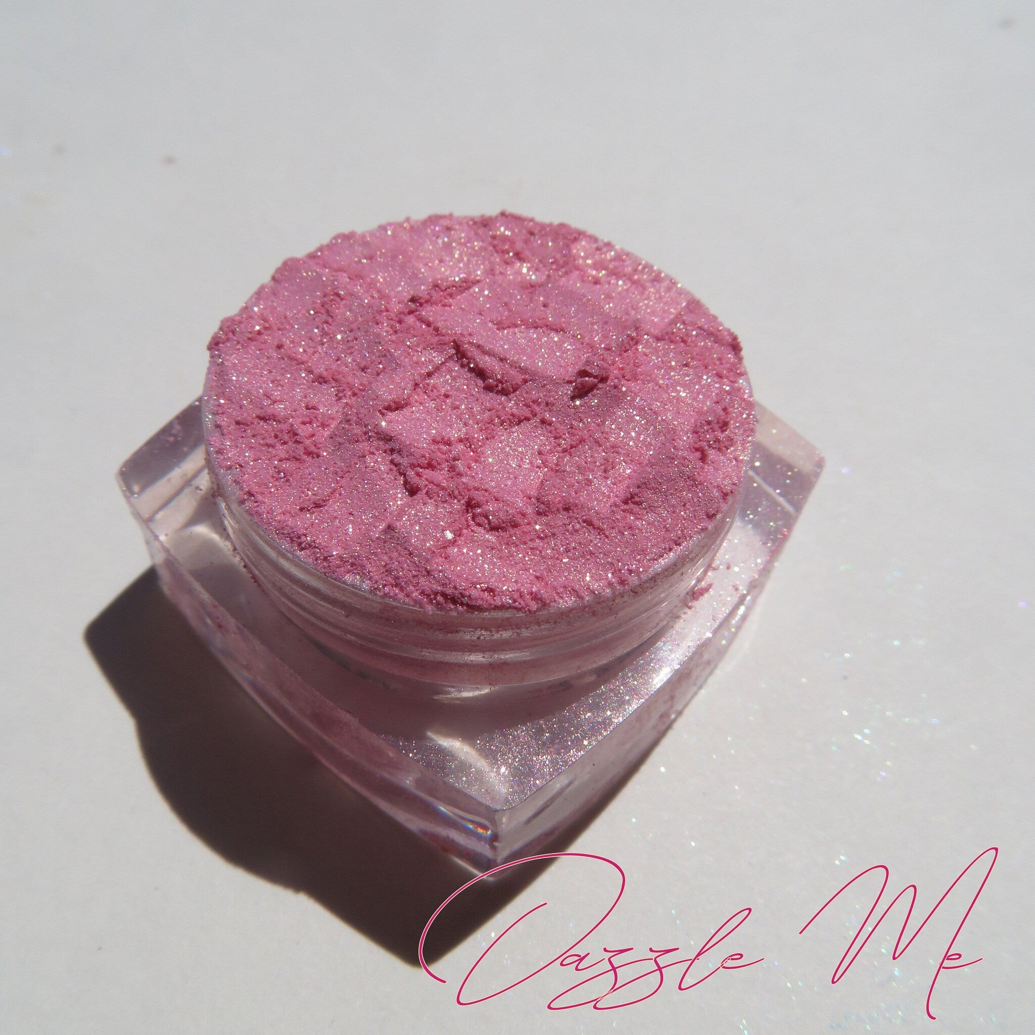 Close-up of loose pink-gold shimmer eyeshadow with sparkling mineral particles in natural light