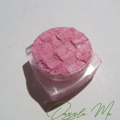 Loose powder eyeshadow in soft pink with golden shimmer, vegan and cruelty-free, shown in a small open jar.