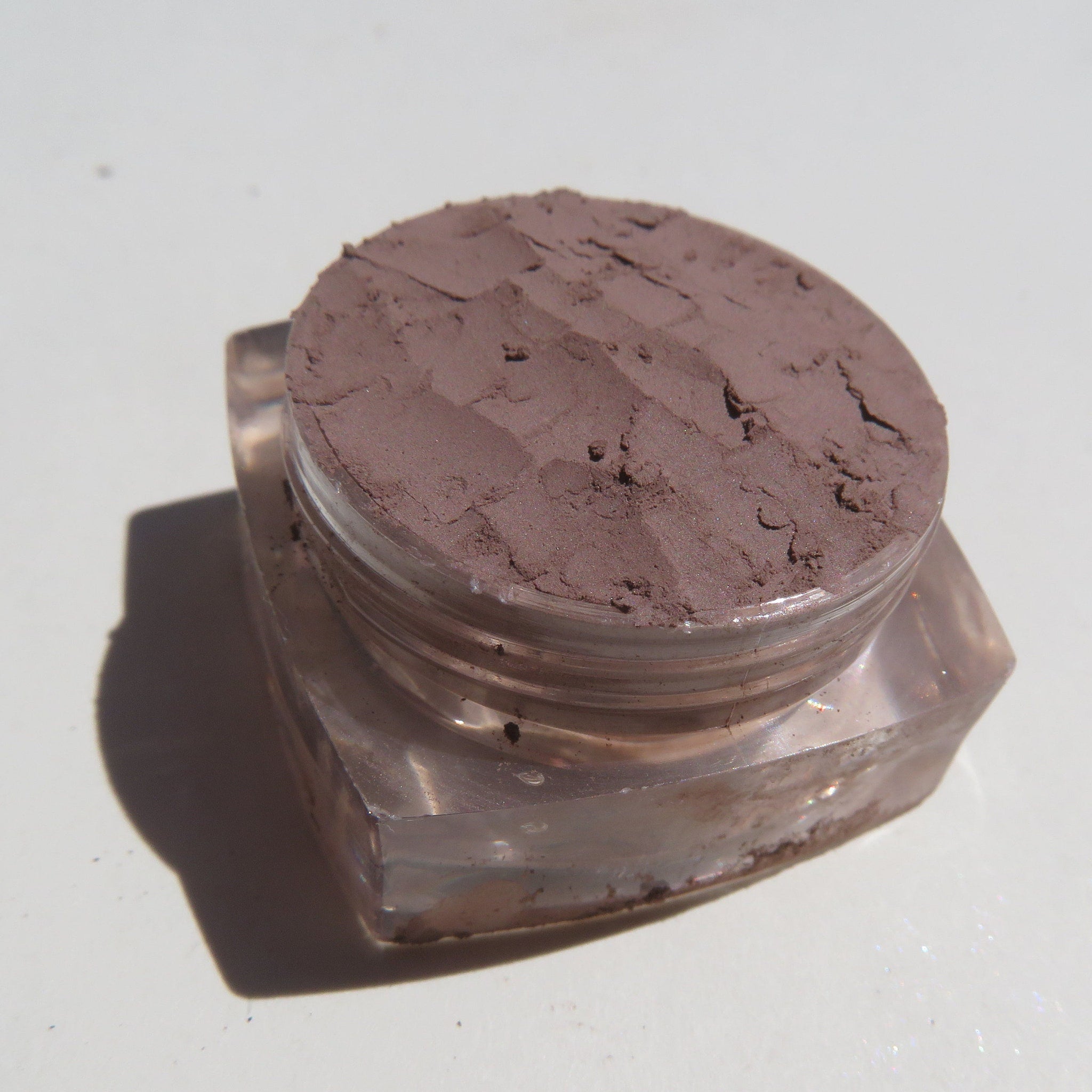 Close-up of matte taupe brown loose mineral eyeshadow powder in eco-friendly packaging with soft texture