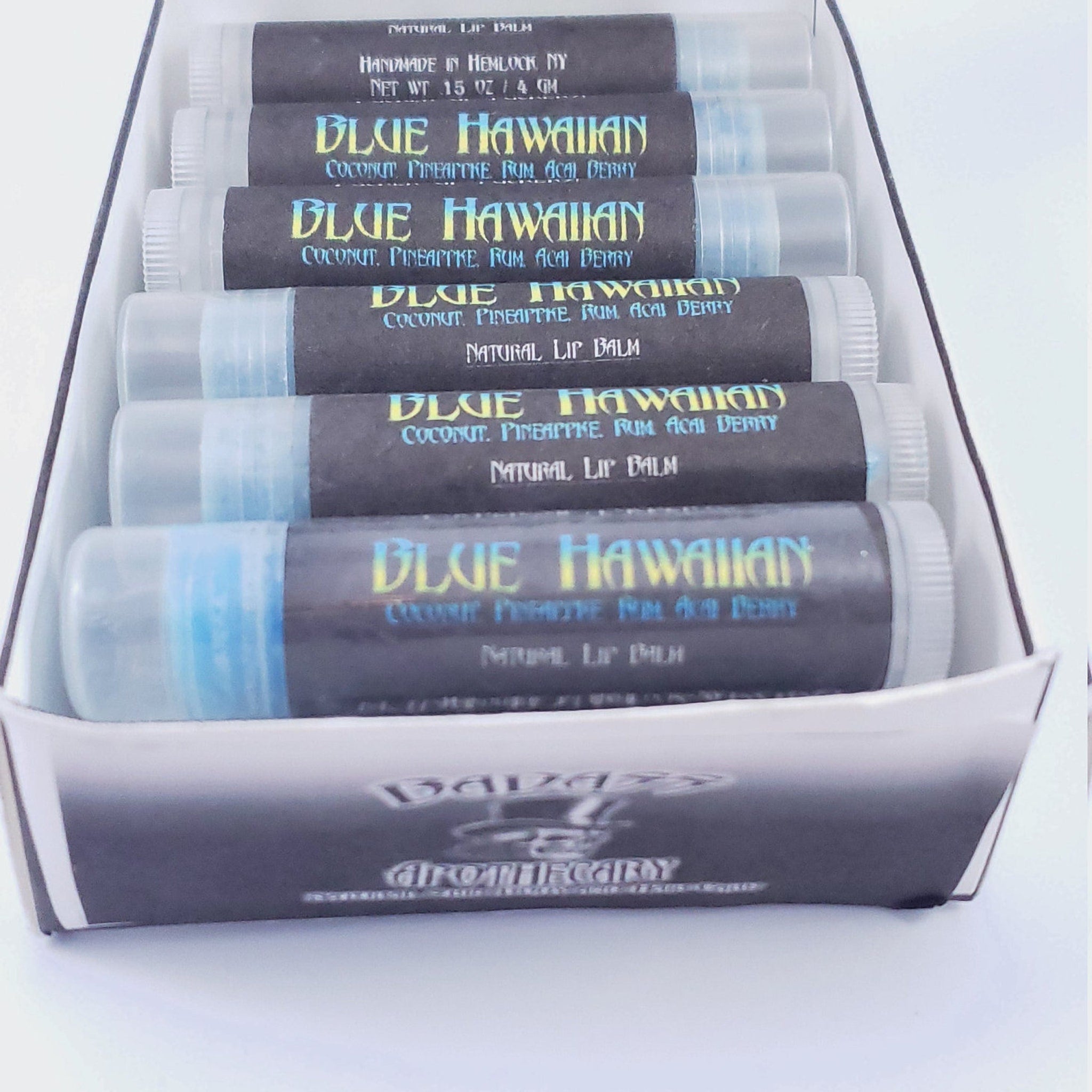 Lip balm tubes with blue and black labels, clear plastic, and Badass Apothecary brand visible in box