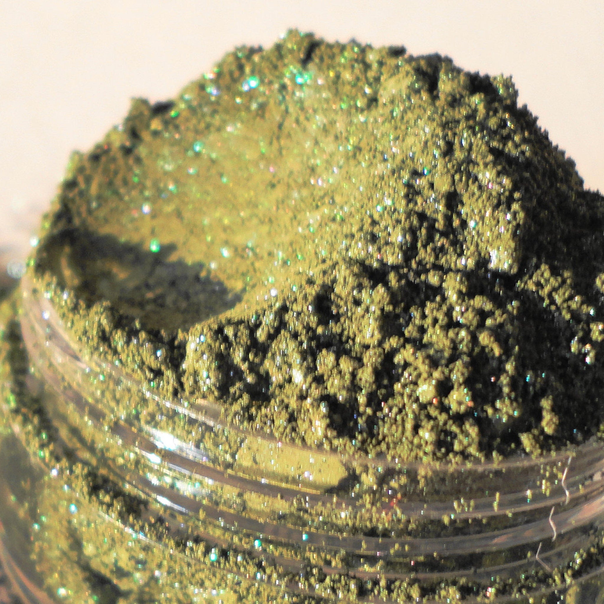 Close-up of forest green shimmer eyeshadow pan showing mineral texture and reflective particles