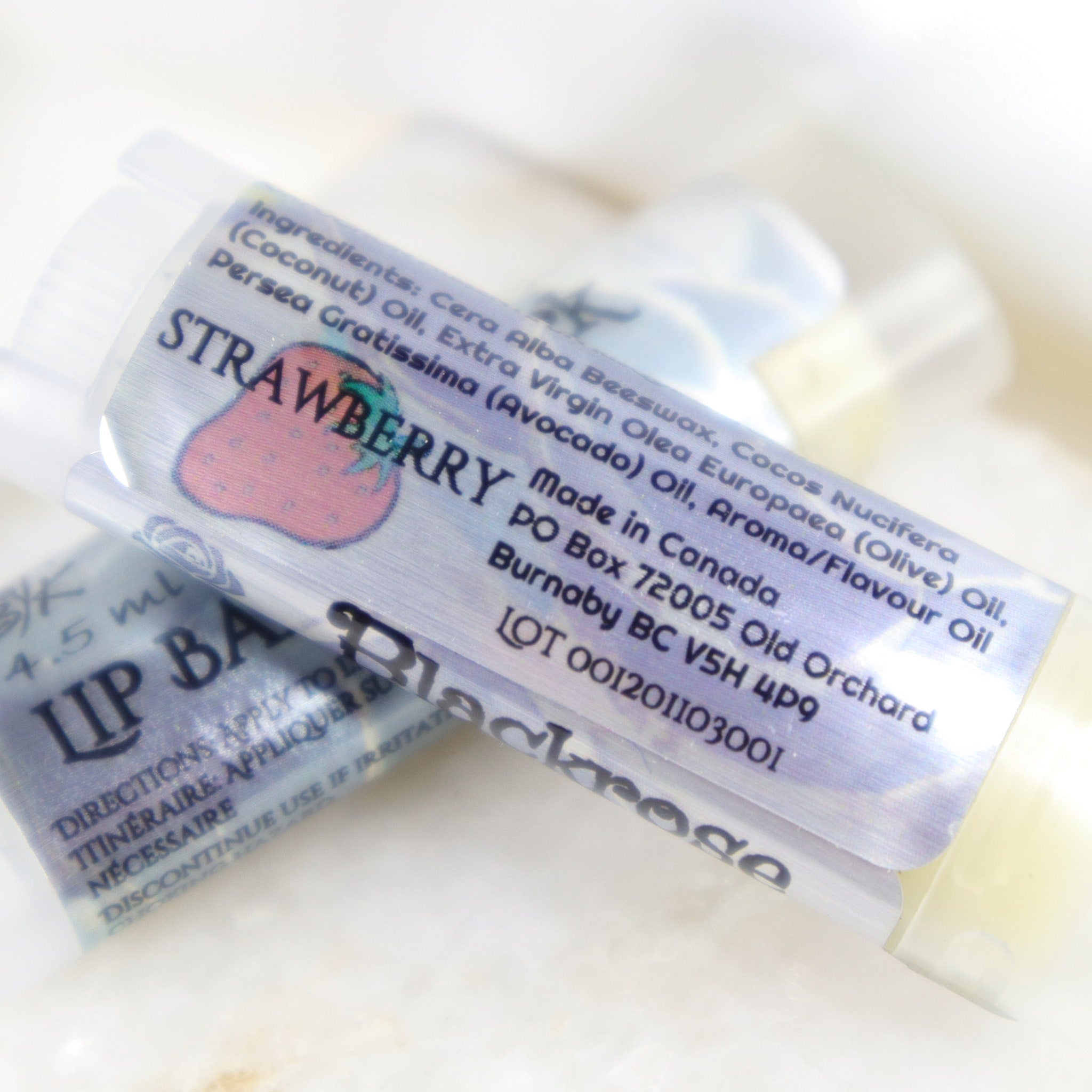 Lip balm tube with white and blue label, strawberry graphic, BlackroseKraftwork text visible