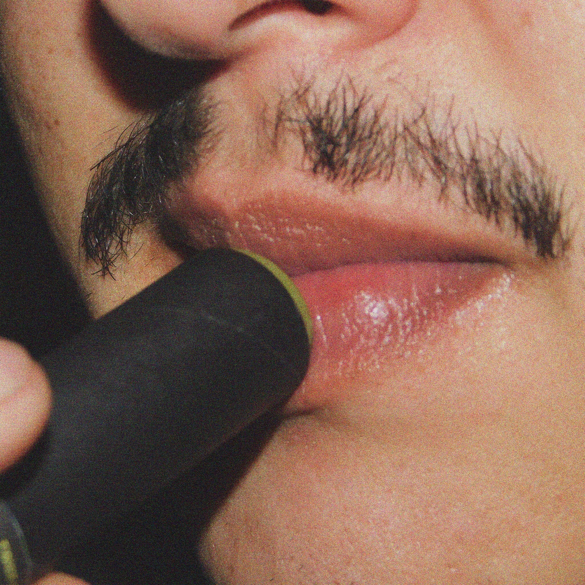 Lipstick application, black lipstick applicator with green trim, on red lips, close up view