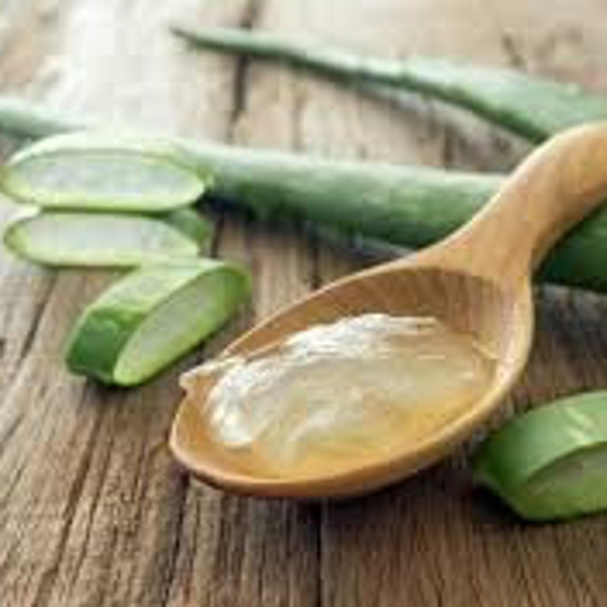 Aloe vera slices with green color and gel in wooden spoon on a wooden surface