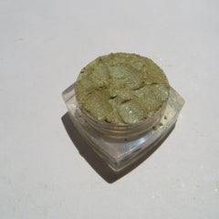 Hand applying shimmering green and gold vegan mineral eyeshadow with fingertip for bold eye look