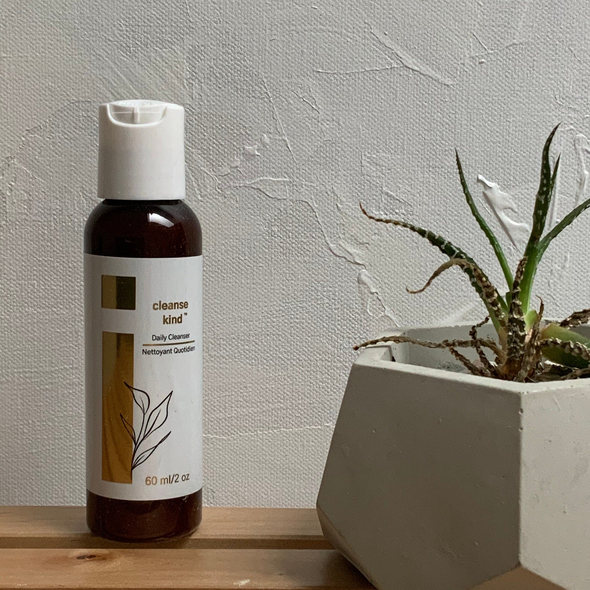 Facial cleanser bottle with white and brown label, white cap, Cleanse Kind brand