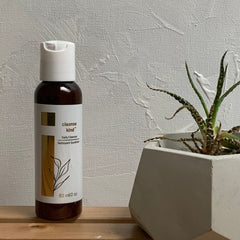 Facial cleanser bottle with white and brown label, white cap, Cleanse Kind brand