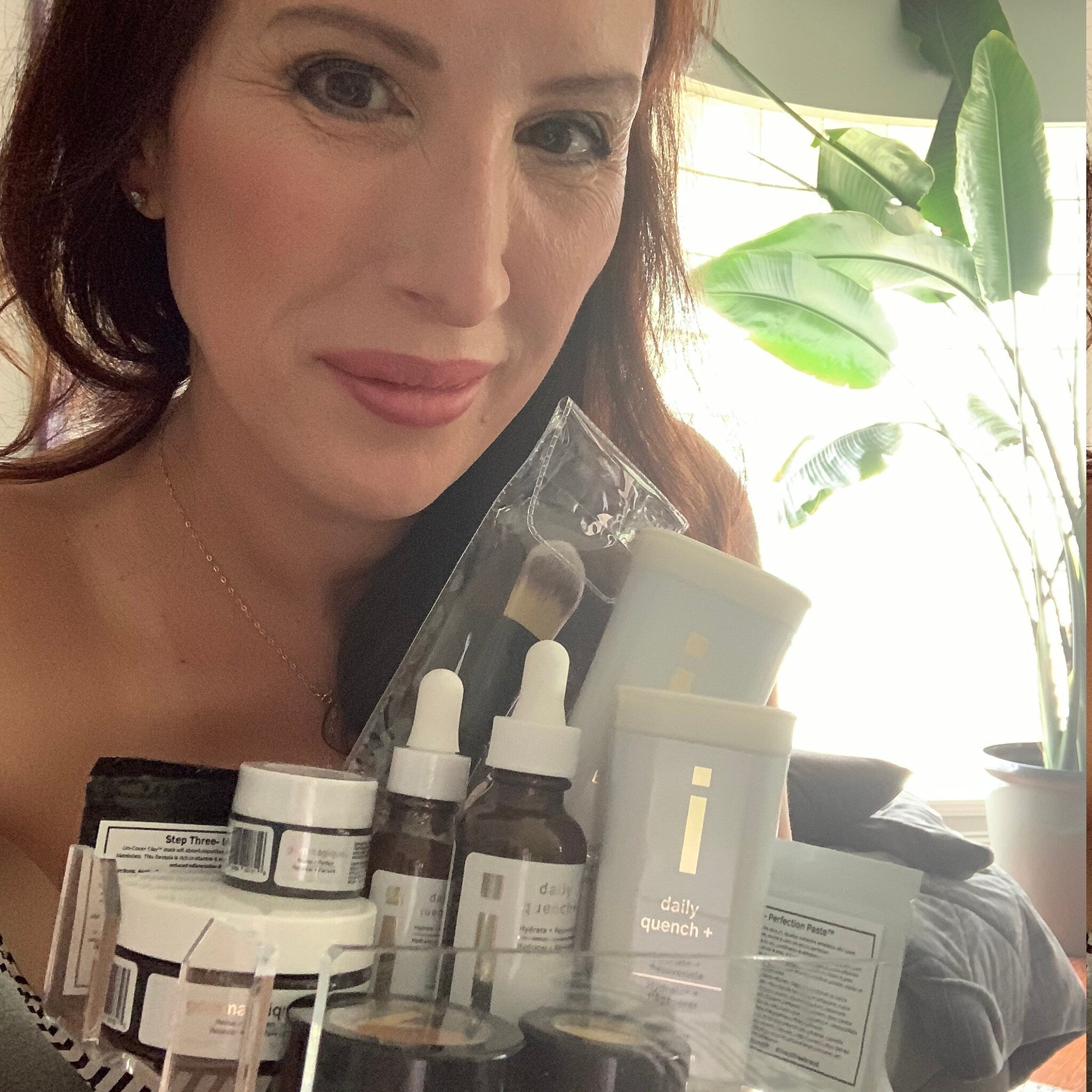 Skincare products in clear plastic case with white and brown bottles, held by woman