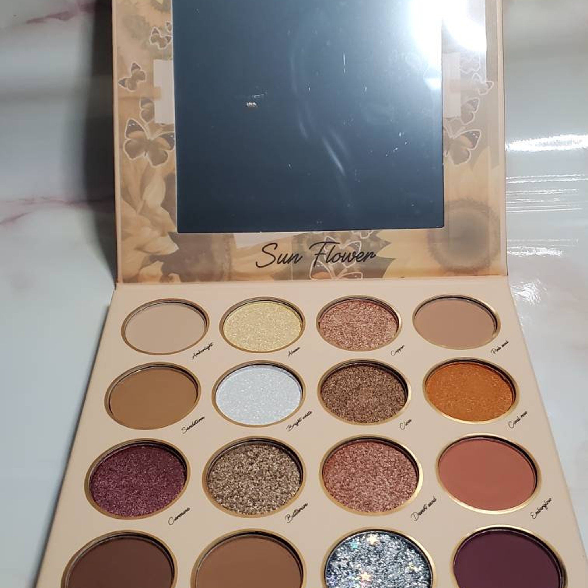 Hand applying shimmery sunflower yellow eyeshadow with a fluffy brush onto eyelid
