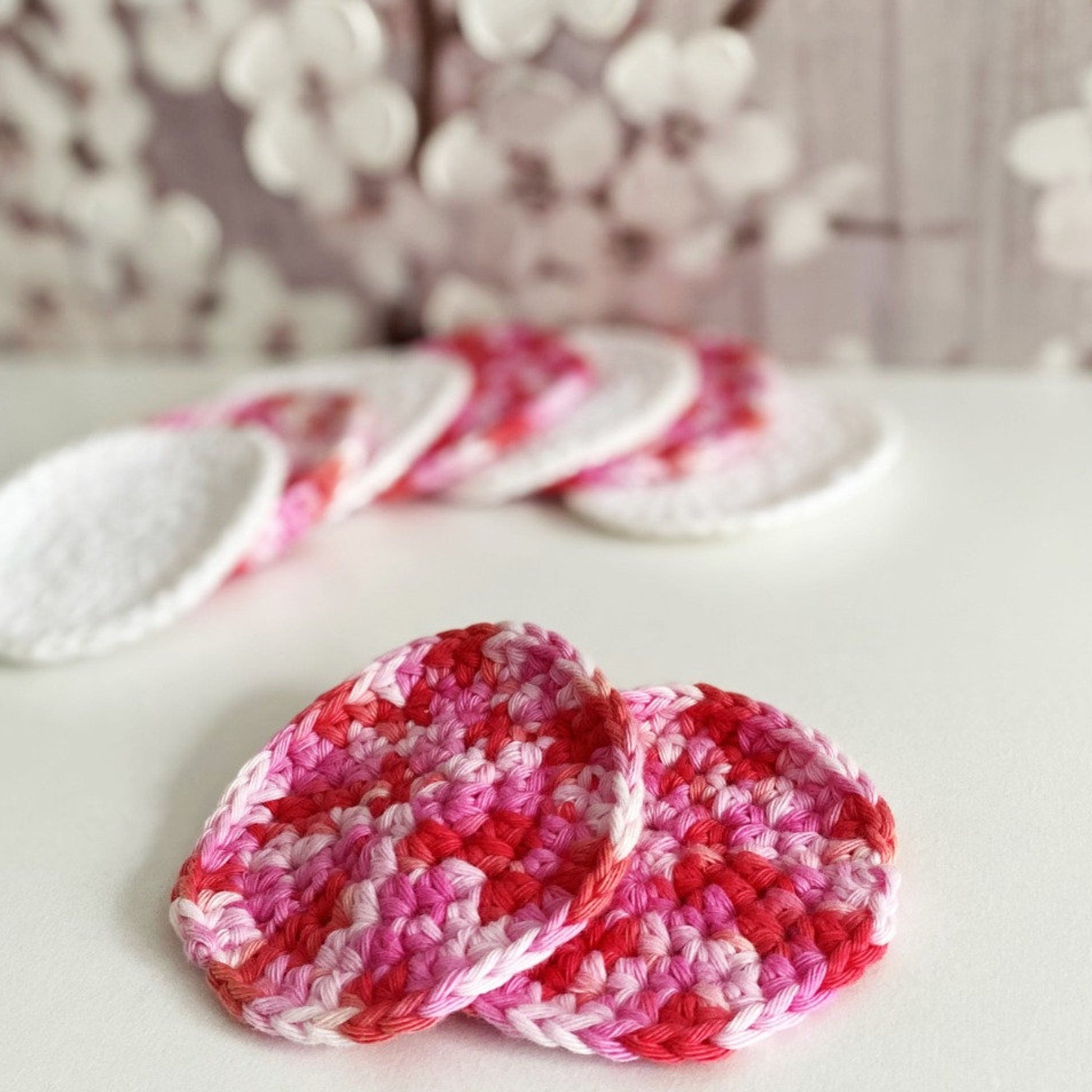 Reusable cotton pads in pink and red crochet, round shape, for skincare use