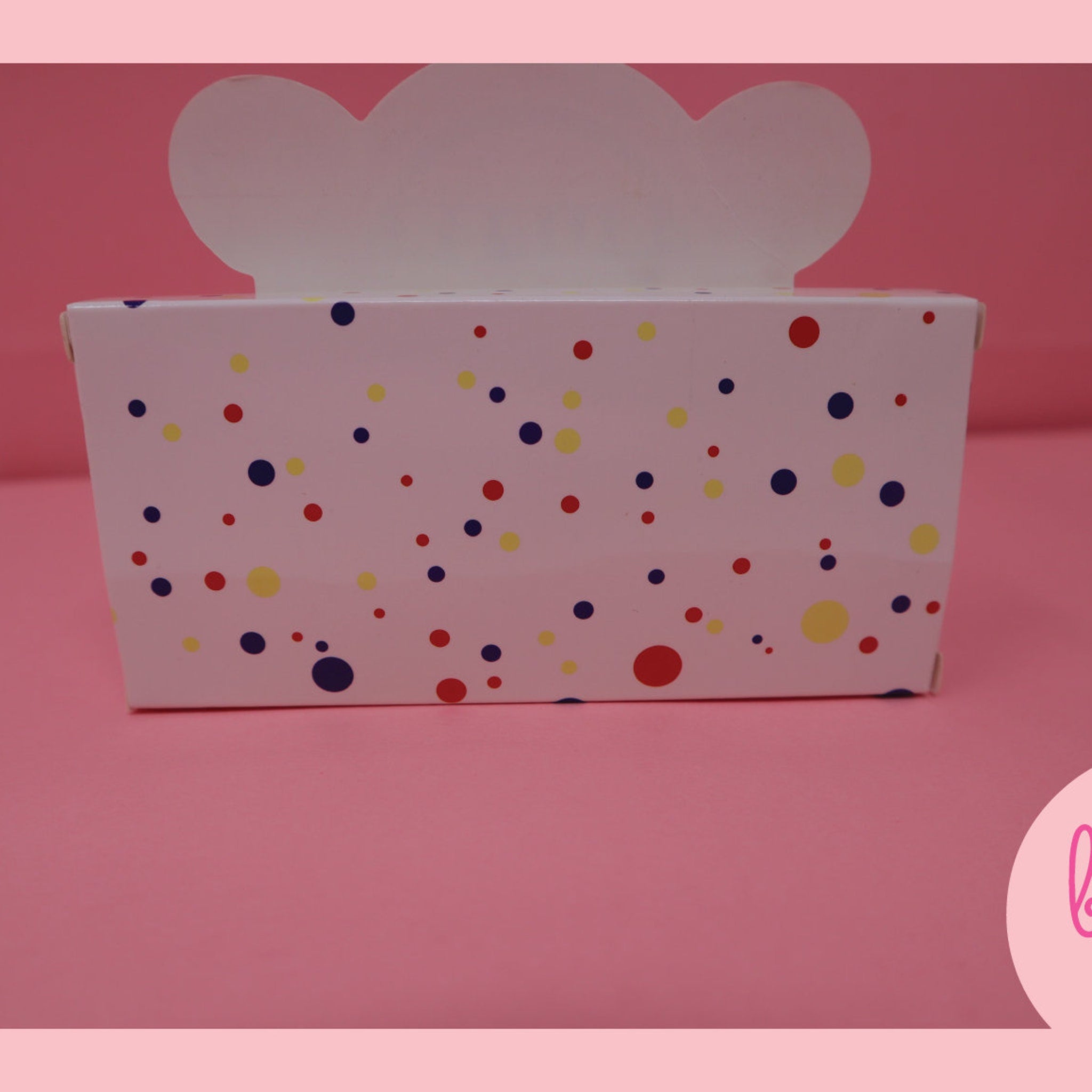 Box with polka dots, white, pink, and blue spots, with a cloud shaped top, on a pink background