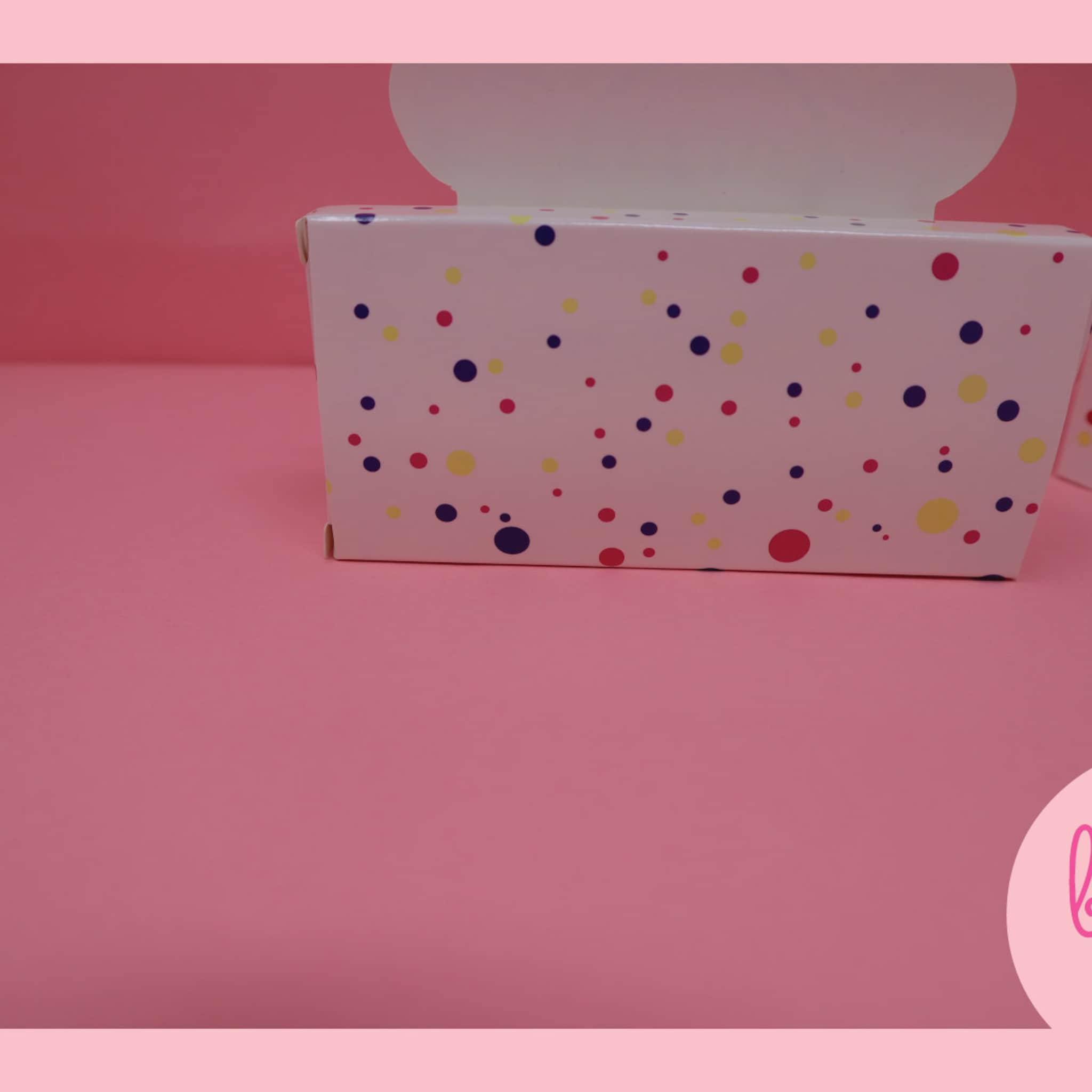 White box with colorful polka dots, on pink background, for gift packaging