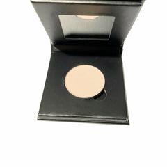 Hand applying barely bisque eyeshadow with fingertip to eyelid, showcasing soft matte finish in refillable paperboard compact