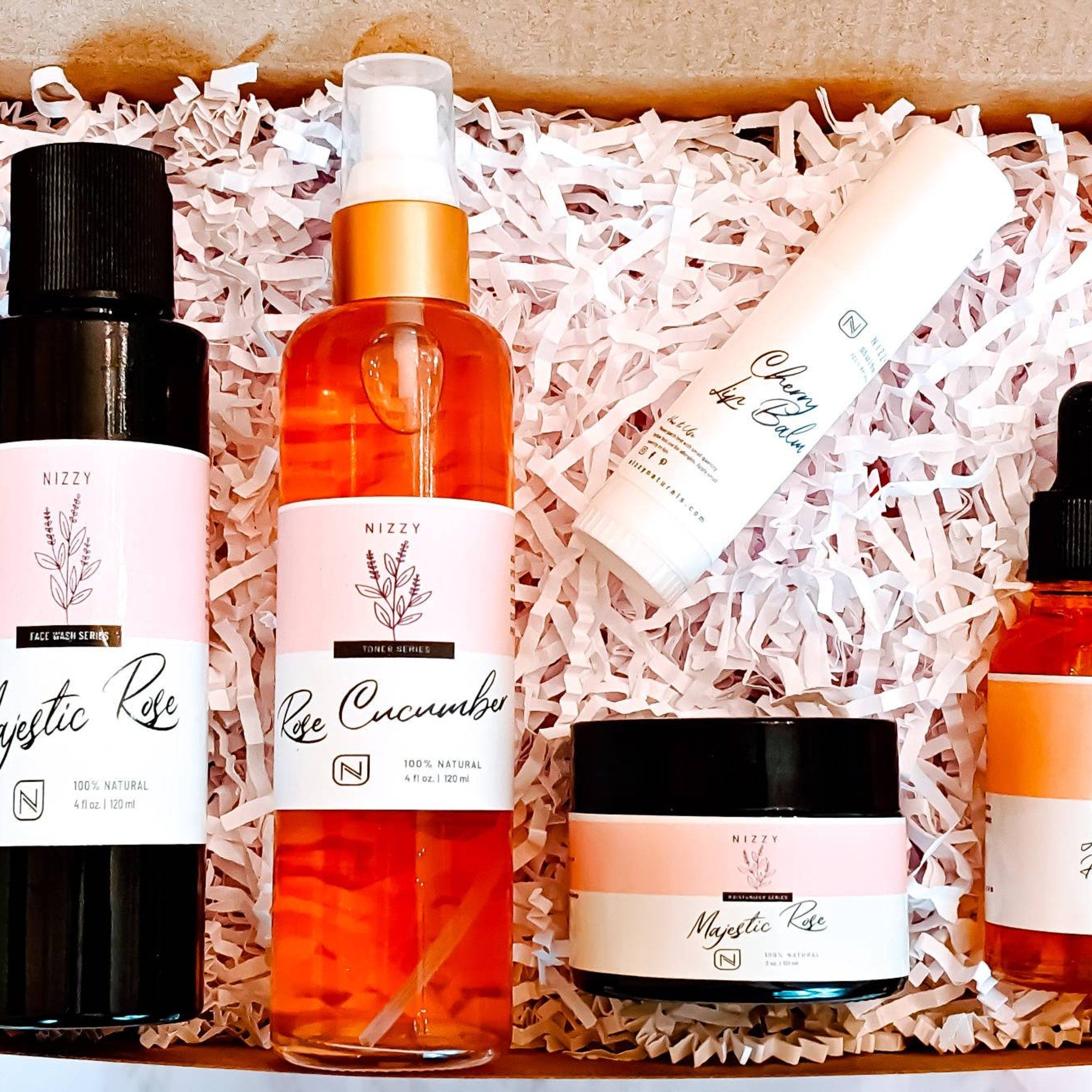 Skincare gift set with black, orange, and white bottles, and shredded paper packaging, NIZZY brand