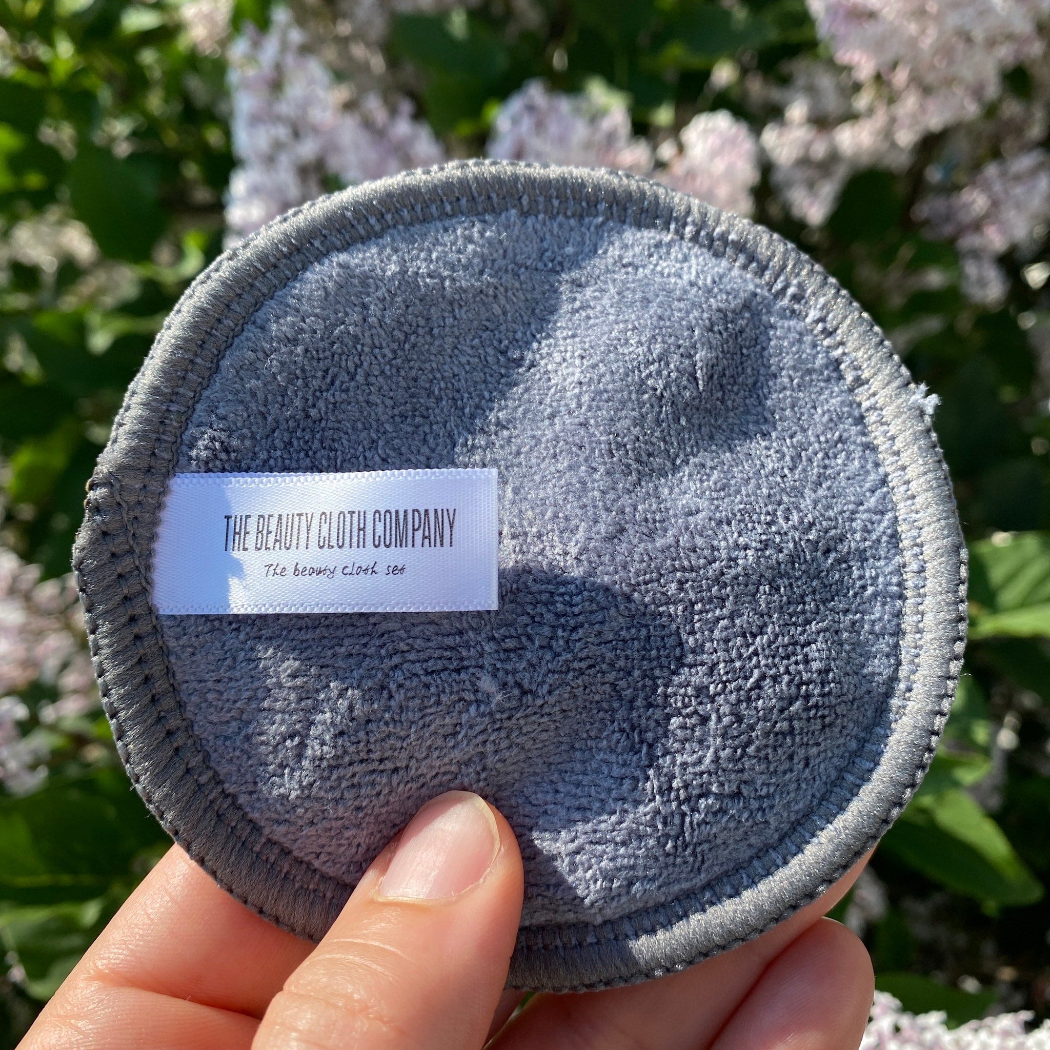 Reusable makeup remover pad, gray microfiber cloth with stitched edge, The Beauty Cloth Company label