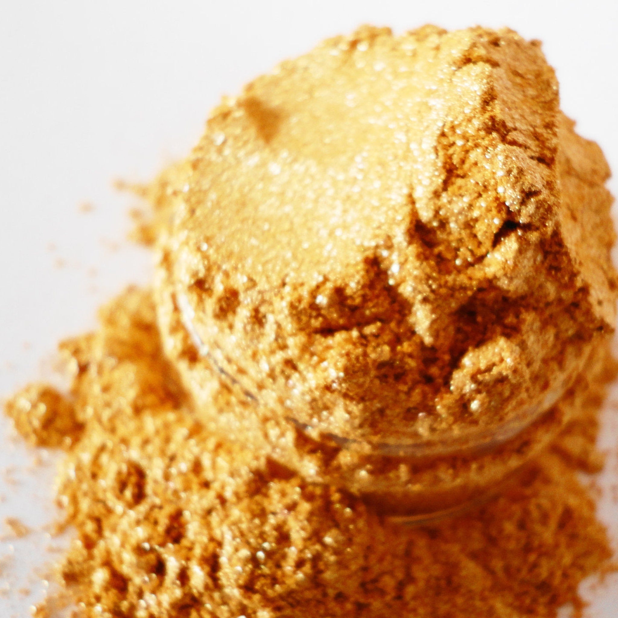 Gold glitter eyeshadow, gold shimmer, loose powder, and spilled product on white background