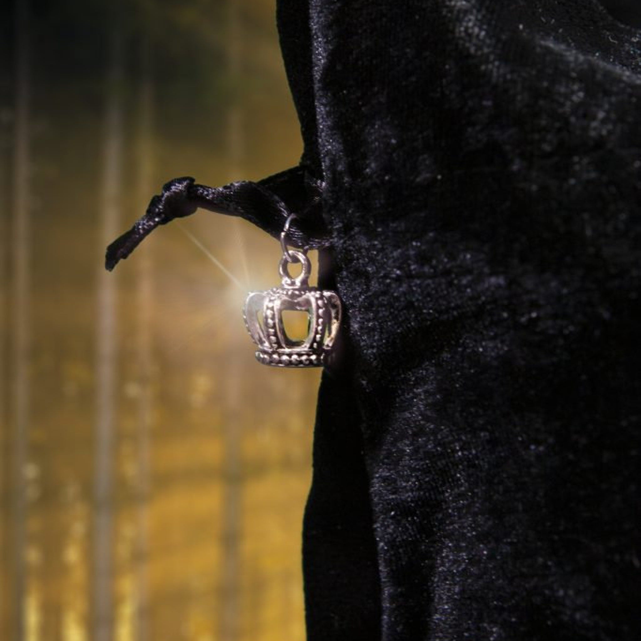 Silver crown charm pendant with black fabric, shiny detail, and ornate design.