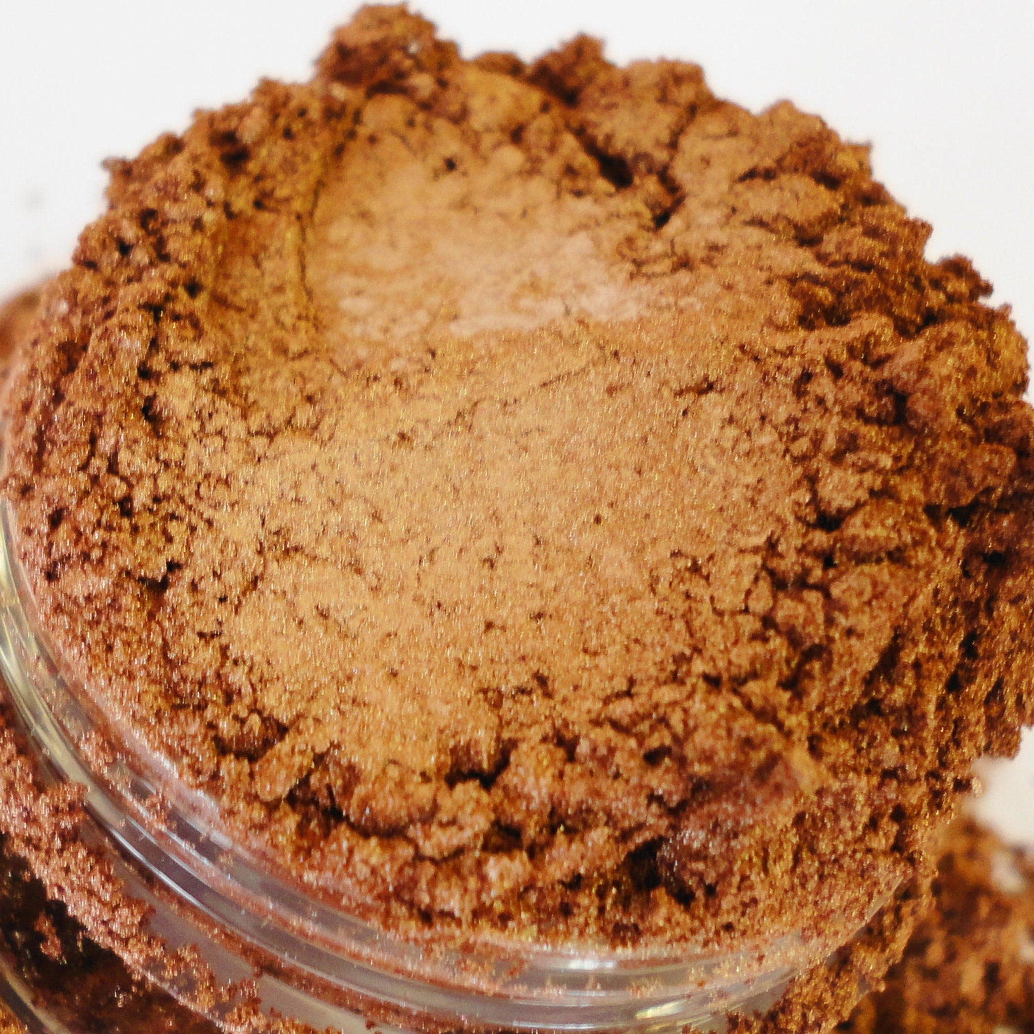 Side view of metallic gold-copper eyeshadow jar showing shimmer texture and sifter lid details