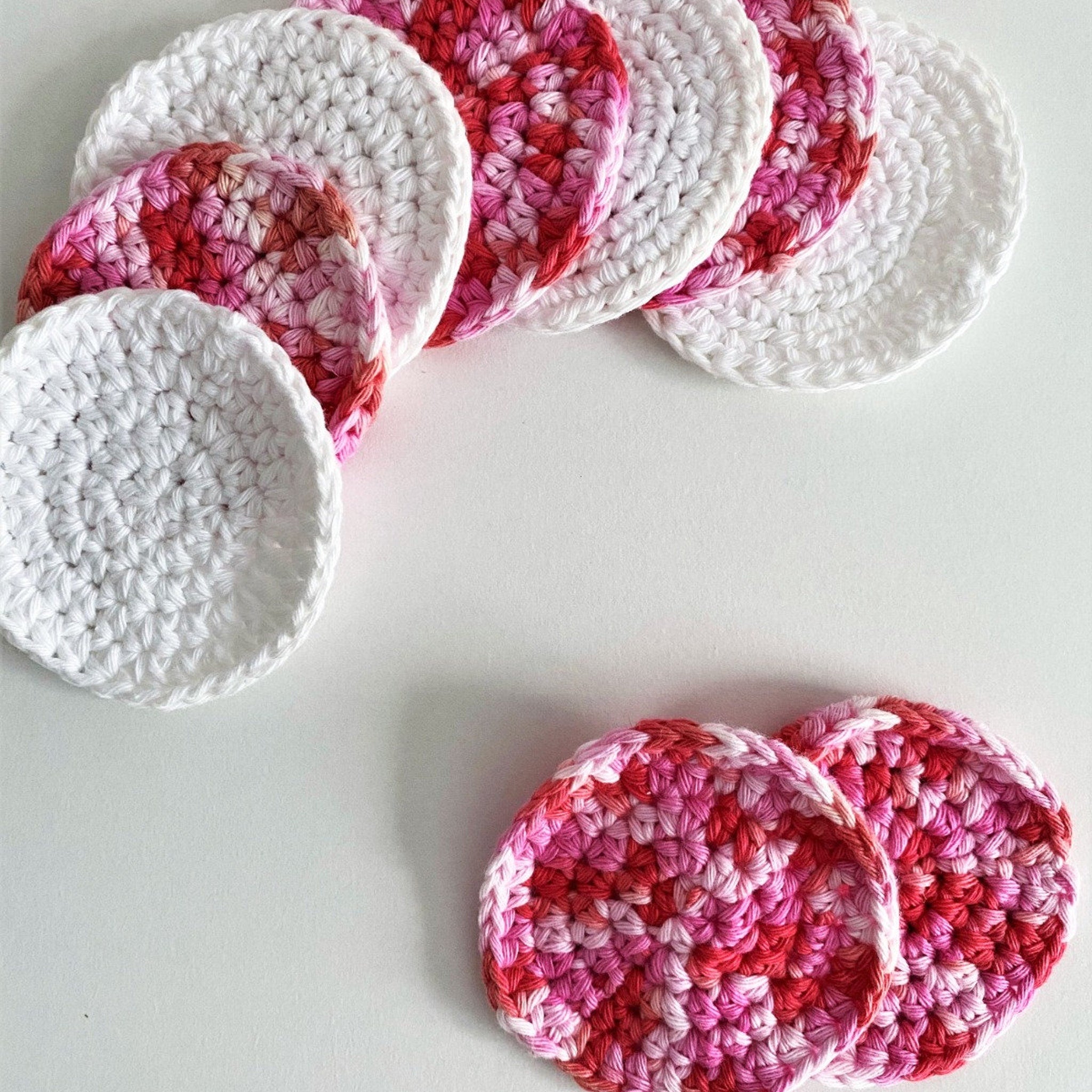 Crochet face rounds in white, pink, and red, arranged on a white surface