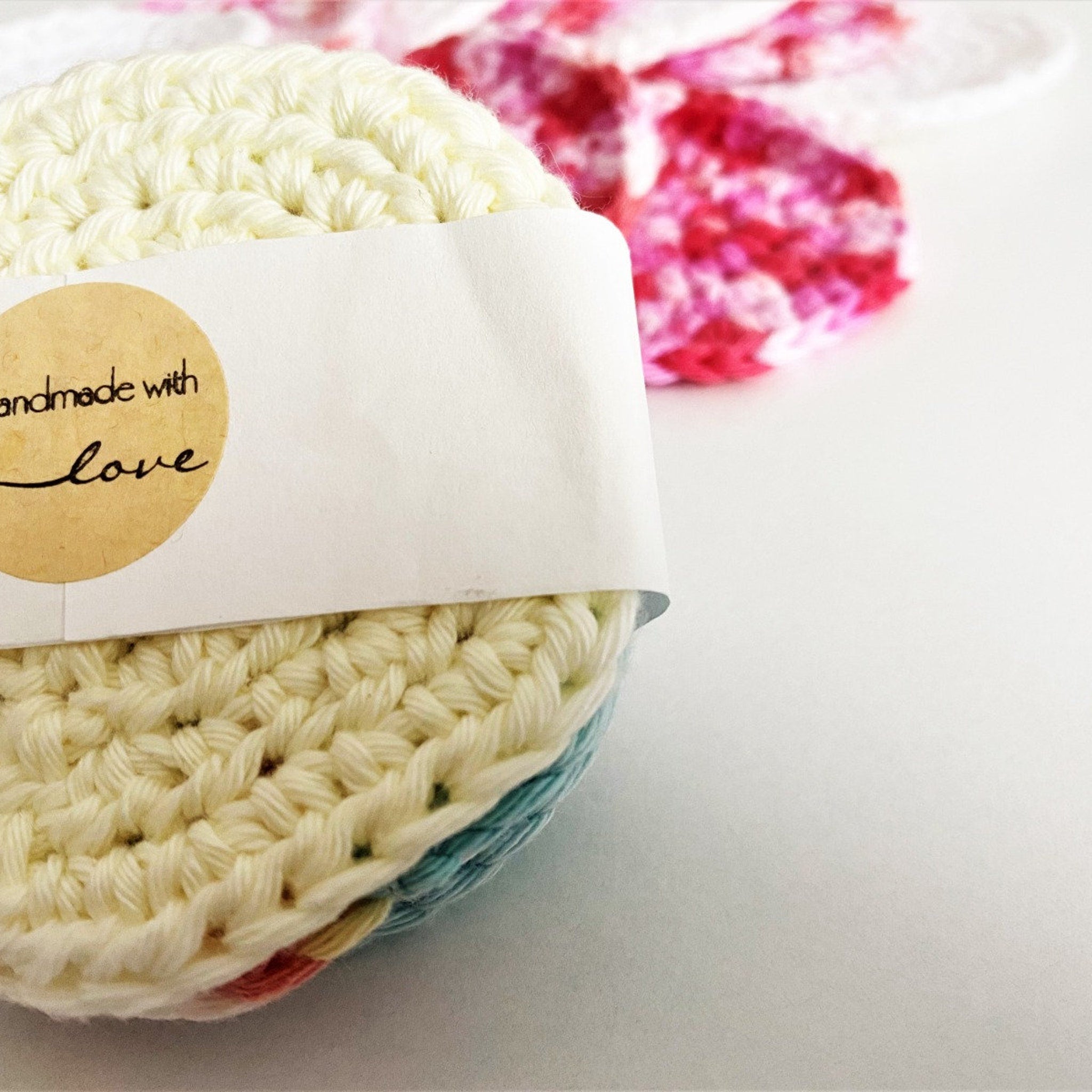 Crochet circle, cream yarn, handmade with love sticker, pink floral background