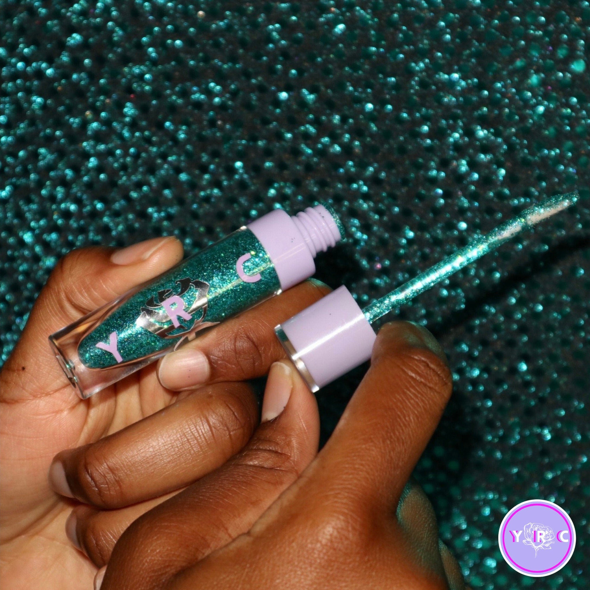Close-up of shimmering teal and seafoam green eye shadow duo with wave-like texture in compact palette