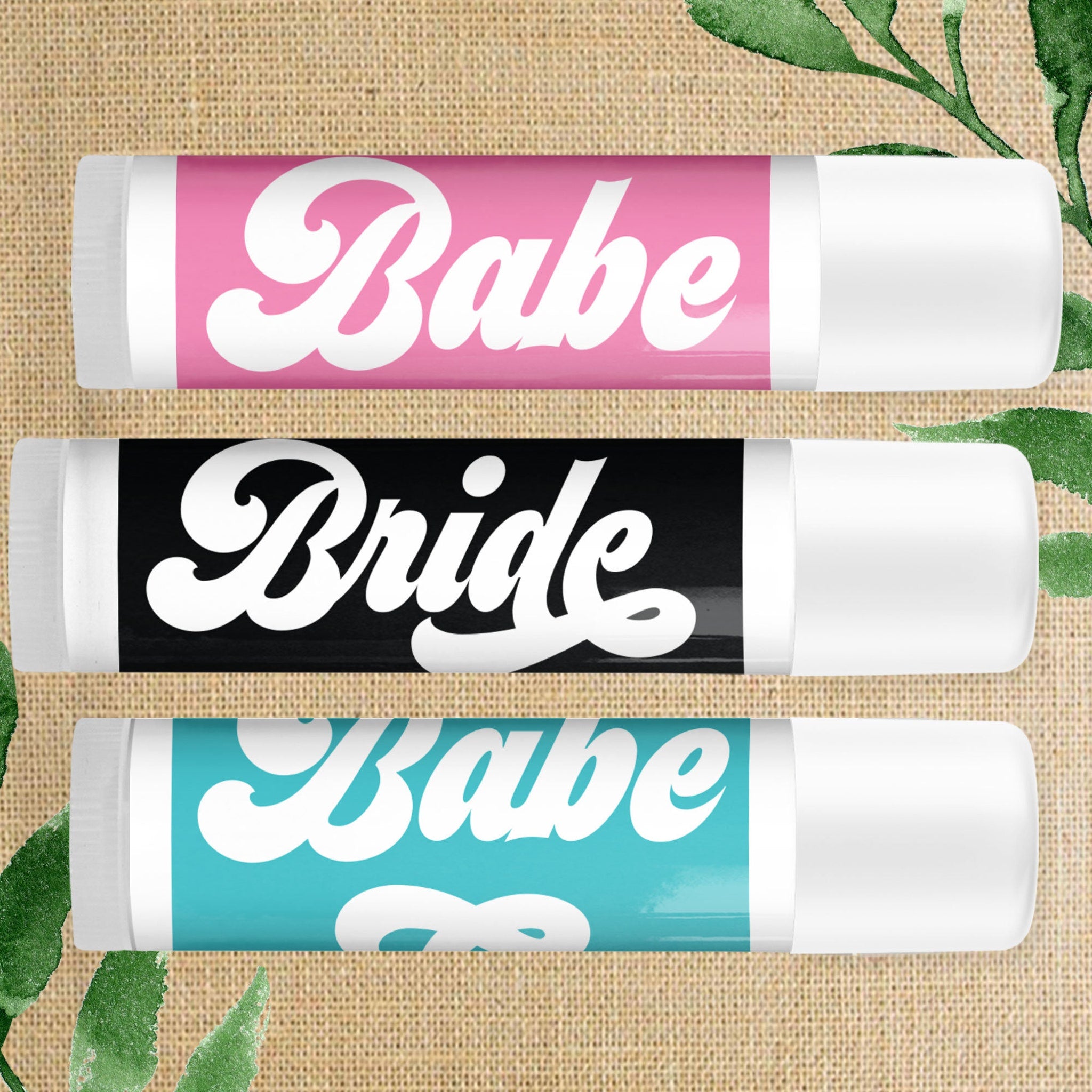 Lip balm tubes with pink, black, and teal color bands, white text, and white caps