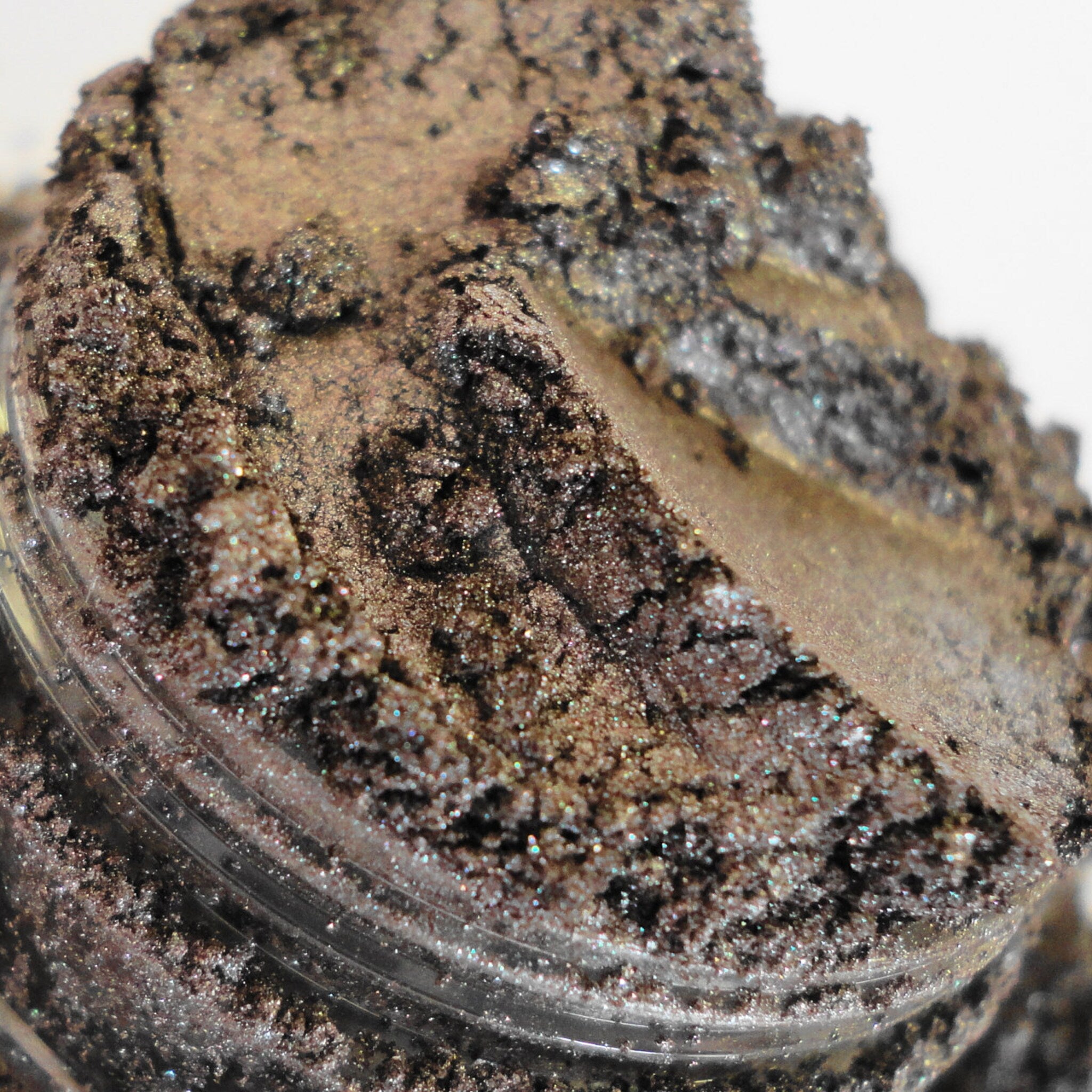 Close-up of shimmering dark brown vegan eyeshadow powder in sifter jar, showing rich pigmentation and fine texture
