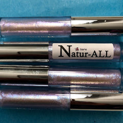 Lip gloss tubes with iridescent purple shimmer and silver caps, "Natur-ALL" brand visible