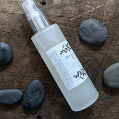 Facial cleanser bottle with frosted glass, silver pump, and "AGELES" label on wood surface