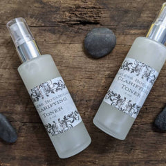 Clarifying toner bottles with frosted glass, silver pump, and Ageless Botanicals label on wood surface