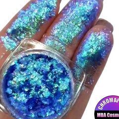 Vibrant prismatic eyeshadow flakes in a clear jar showcasing multicolor metallic shimmer and reflective chrome particles