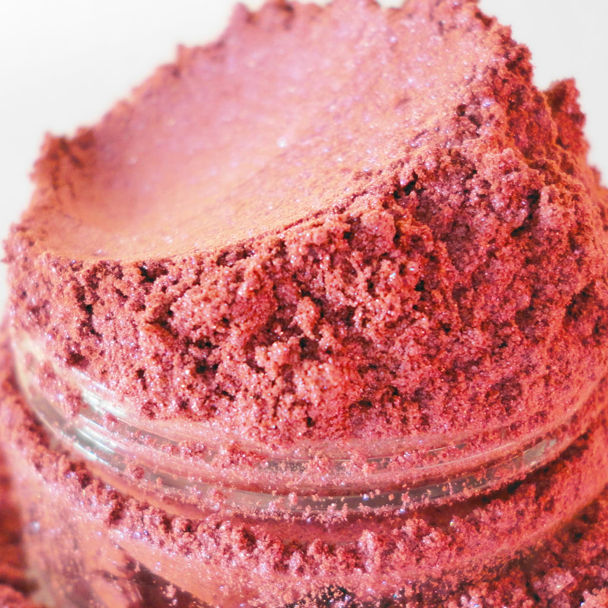 Pink eyeshadow powder with glitter, in a glass jar, close-up view